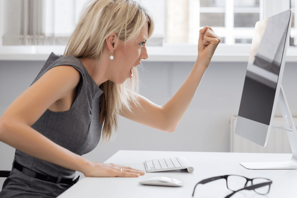 A very frustrated employee because her computer isn't working properly, emphasizing the need for outsourced IT technical support services to quickly resolve issues and restore productivity.