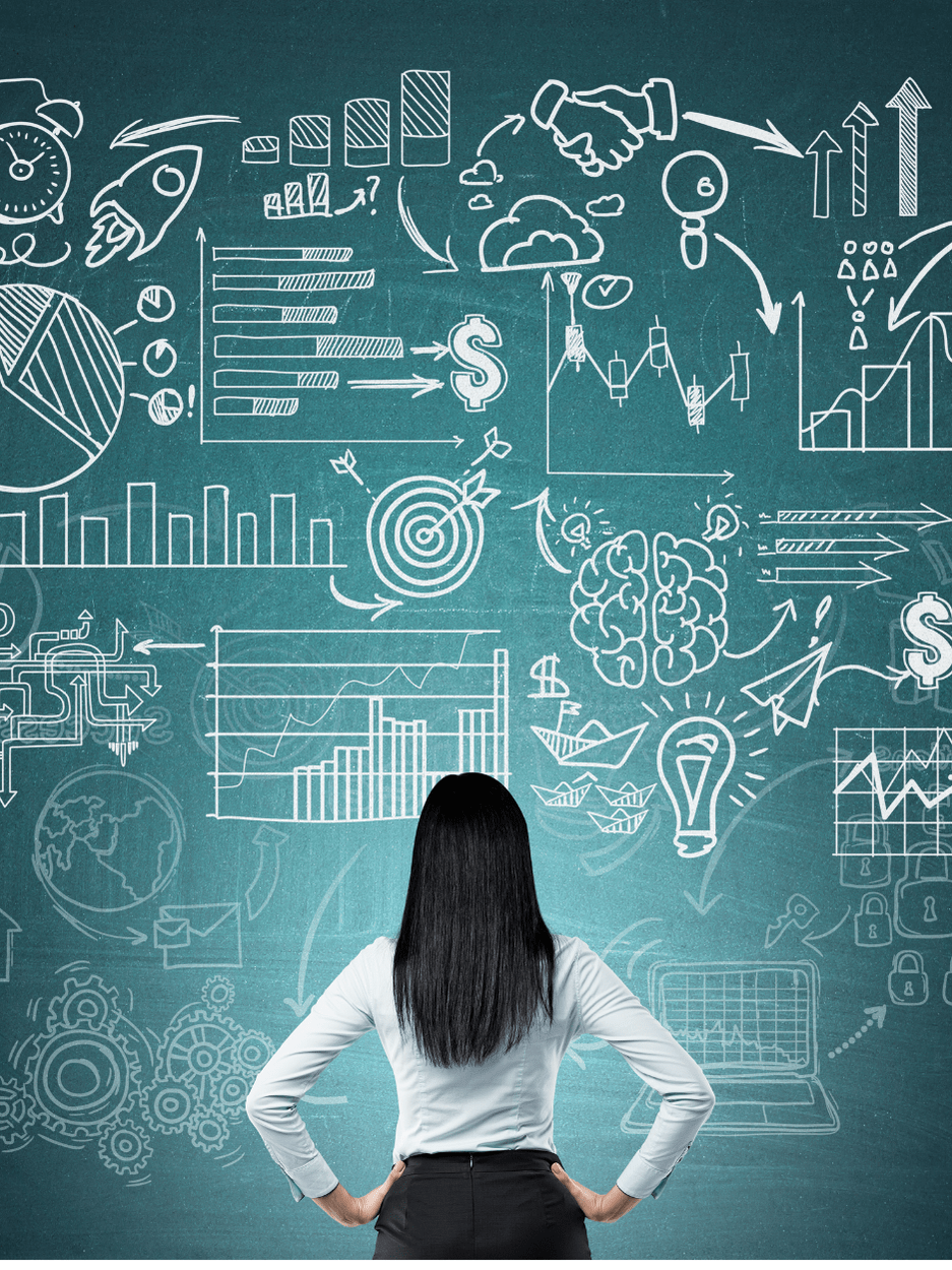 A businesswoman stands with hands on hips in front of a chalkboard filled with complex charts, graphs, and tech strategy symbols representing planning and decision-making.