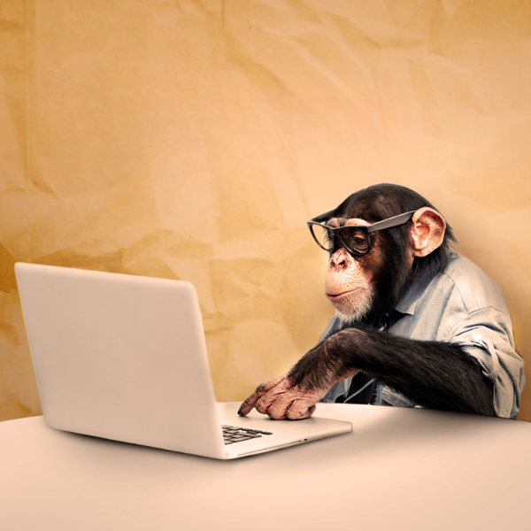 A chimpanzee wearing glasses and a shirt using a laptop, symbolizing outdated or unprepared approaches to cybersecurity.