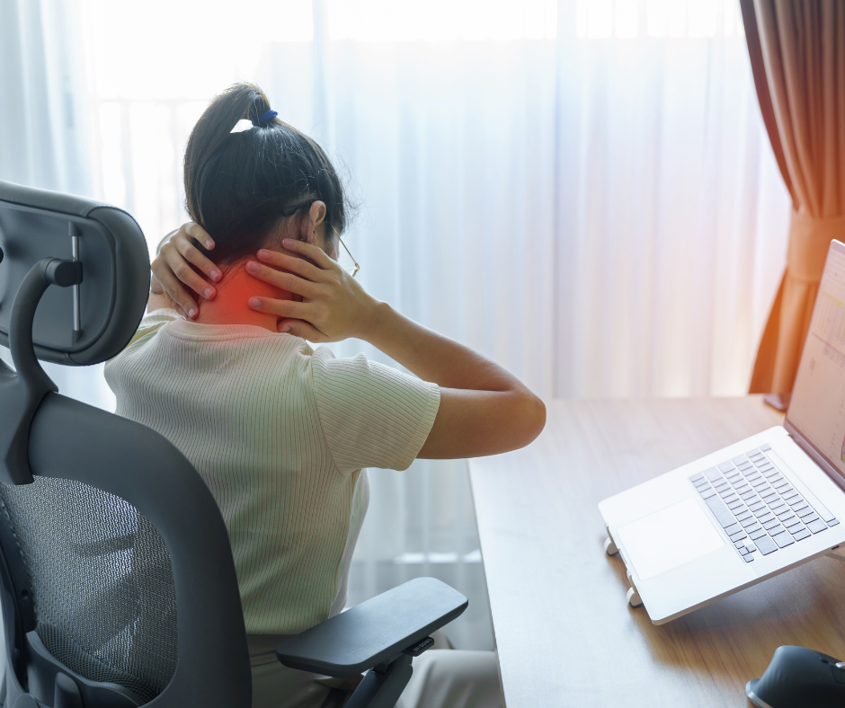 Employee sitting at a desk with poor ergonomics, holding neck in pain while working on a laptop.